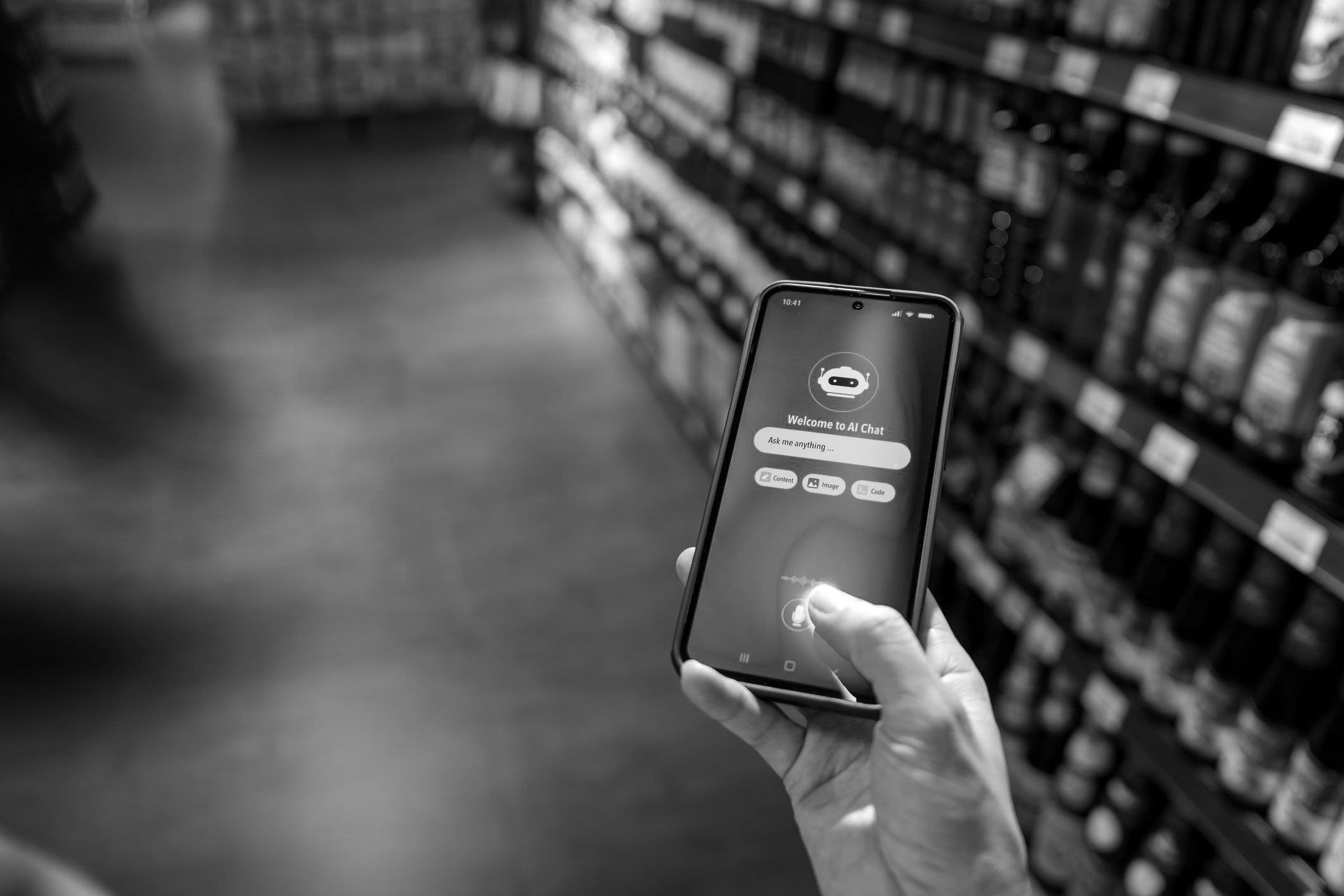A person uses an AI chatbot app on a smartphone inside a grocery store, with shelves of products in the background.