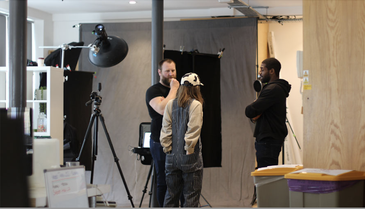 People in studio standing facing each other, discussing the shot of an ad