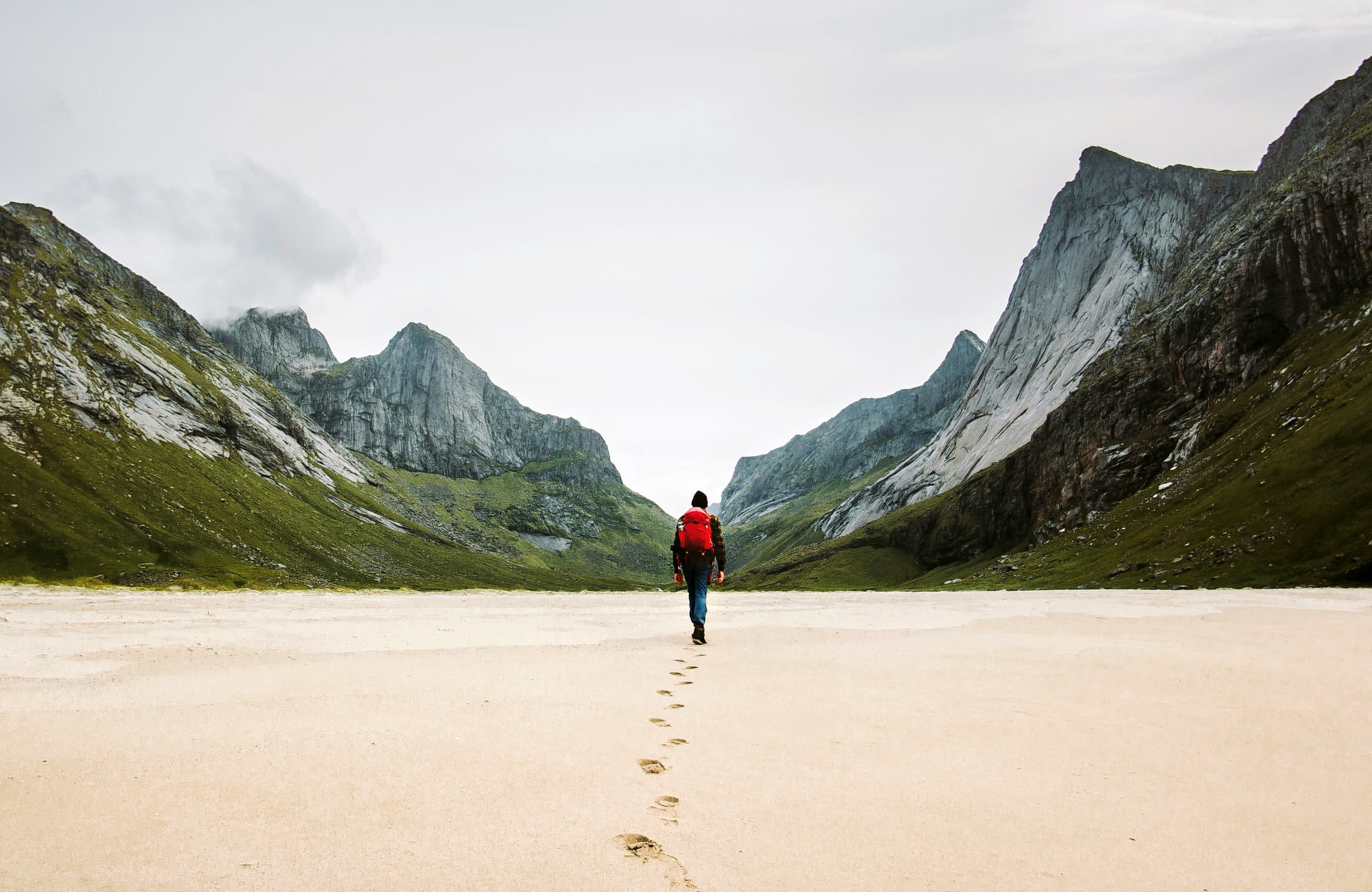 Person with red rucksack in mountainous nature.